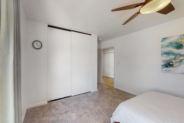 carpeted bedroom with ceiling fan, baseboards, and a closet