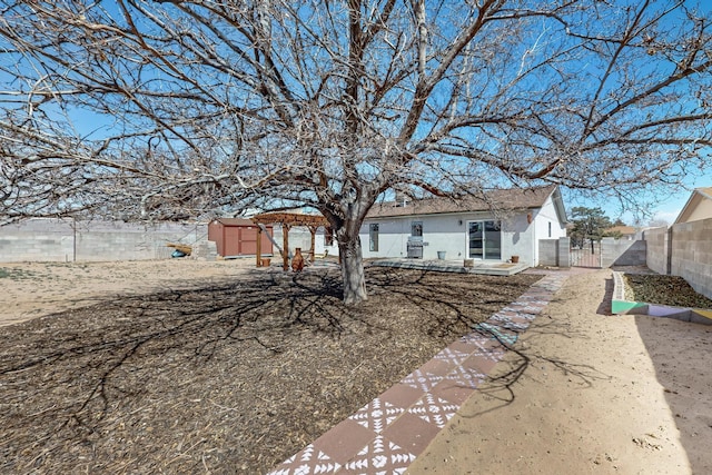 back of house with a gate, fence, and stucco siding