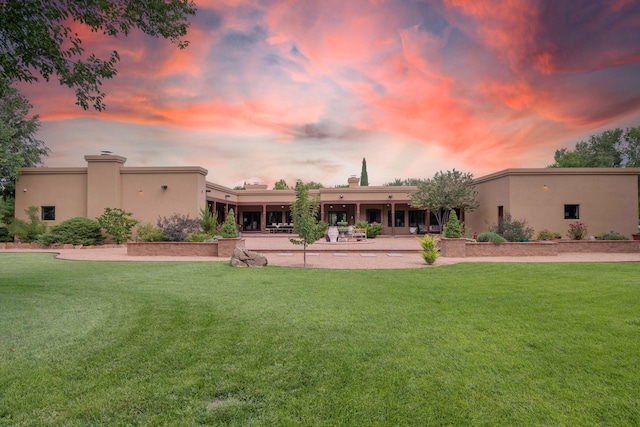 rear view of property featuring stucco siding and a yard