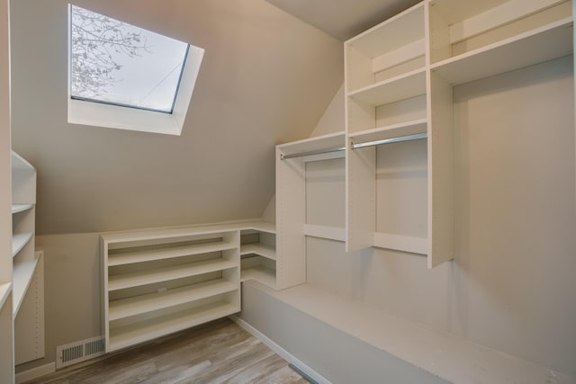 walk in closet with a skylight, visible vents, and wood finished floors