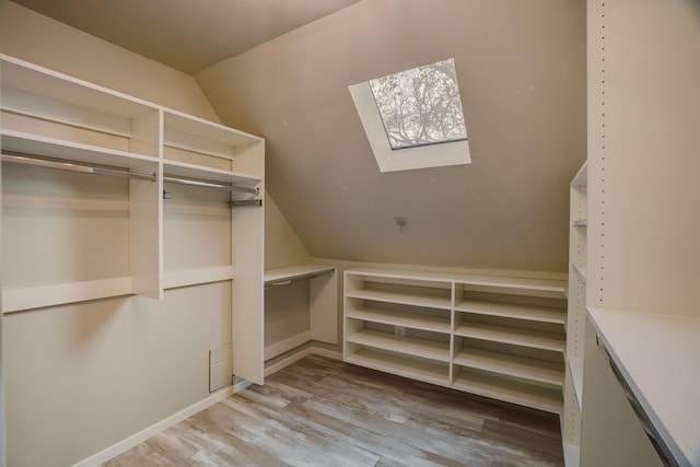 spacious closet with vaulted ceiling with skylight and light wood-style floors