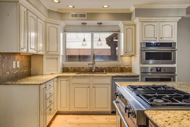 kitchen with visible vents, cream cabinetry, a sink, and decorative light fixtures