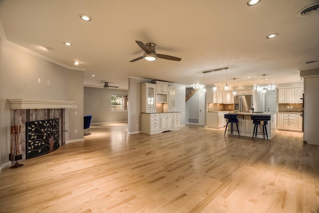 living area with visible vents, crown molding, light wood-style floors, a fireplace, and recessed lighting