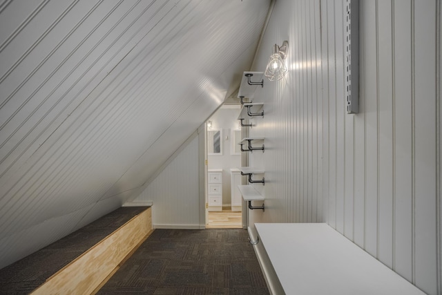 interior space featuring vaulted ceiling and dark colored carpet