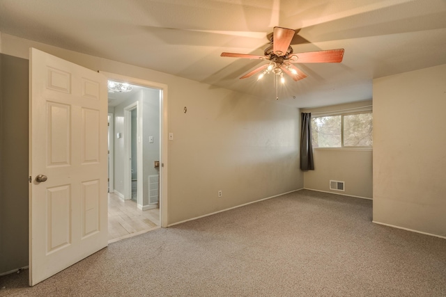 spare room featuring baseboards, visible vents, a ceiling fan, and light colored carpet