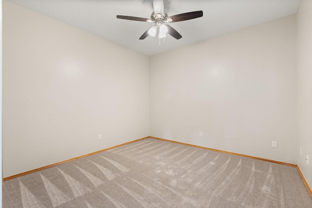 carpeted empty room with ceiling fan and baseboards