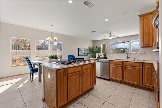 kitchen featuring a sink, light countertops, appliances with stainless steel finishes, a center island, and pendant lighting