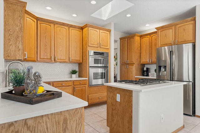 kitchen featuring a skylight, light tile patterned floors, a kitchen island, stainless steel appliances, and backsplash