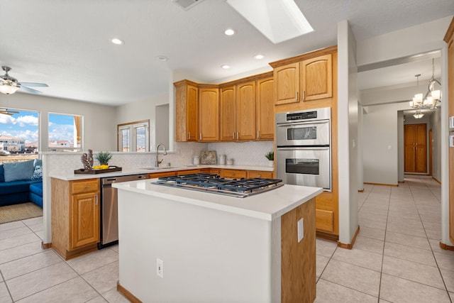 kitchen featuring light tile patterned floors, a center island, stainless steel appliances, light countertops, and a sink