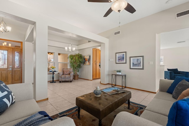 living area featuring ceiling fan with notable chandelier, light tile patterned flooring, visible vents, and baseboards