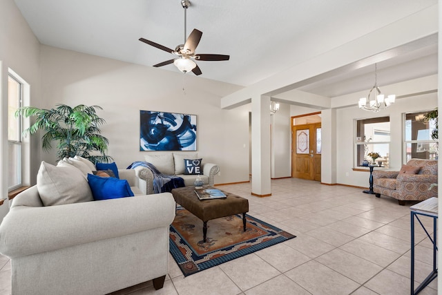 living room featuring ceiling fan with notable chandelier, baseboards, and light tile patterned floors