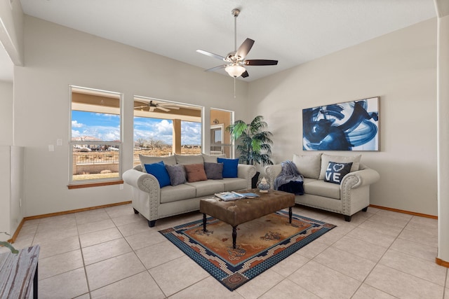 living room with high vaulted ceiling, light tile patterned floors, baseboards, and a ceiling fan