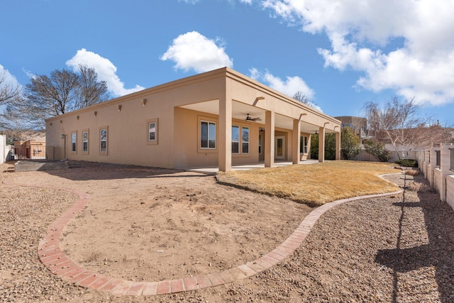 rear view of house with a ceiling fan, a fenced backyard, a patio, and stucco siding