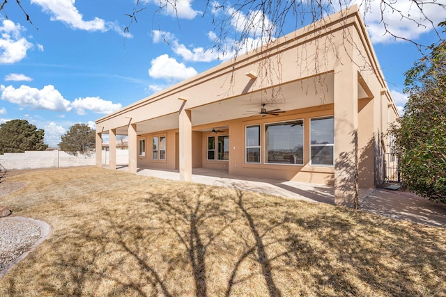 back of property with a patio, fence, a ceiling fan, a lawn, and stucco siding