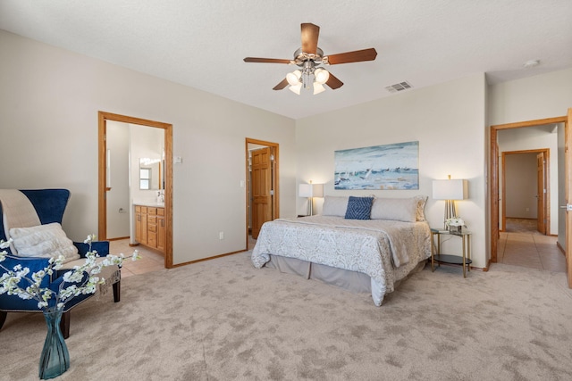 bedroom with visible vents, baseboards, light colored carpet, ensuite bath, and ceiling fan