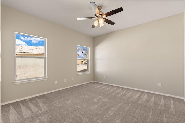 carpeted empty room featuring ceiling fan and baseboards