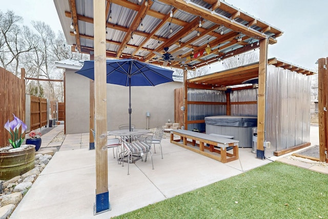 view of patio featuring a hot tub, fence, outdoor dining area, and a ceiling fan