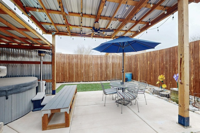 view of patio with a hot tub, ceiling fan, a fenced backyard, and outdoor dining space