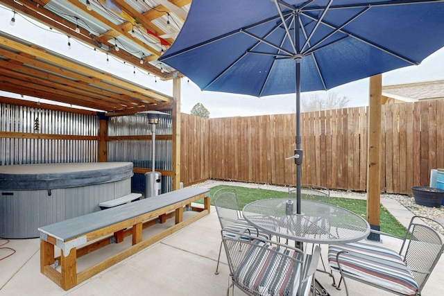 view of patio with a covered hot tub, outdoor dining area, and fence