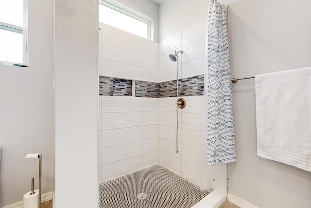 bathroom featuring a tile shower and baseboards