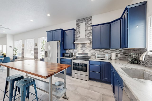 kitchen with backsplash, wall chimney exhaust hood, stainless steel appliances, and a sink