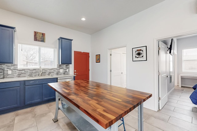 kitchen featuring blue cabinets, a sink, light countertops, tasteful backsplash, and plenty of natural light