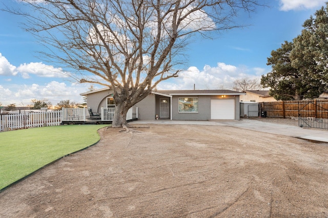 exterior space featuring a garage, brick siding, fence, driveway, and a front lawn