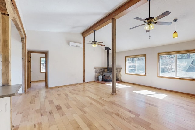 unfurnished living room with a wood stove, baseboards, beamed ceiling, and light wood finished floors