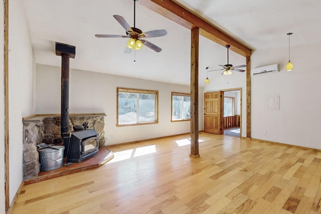 living room featuring beam ceiling, light wood finished floors, an AC wall unit, a wood stove, and baseboards