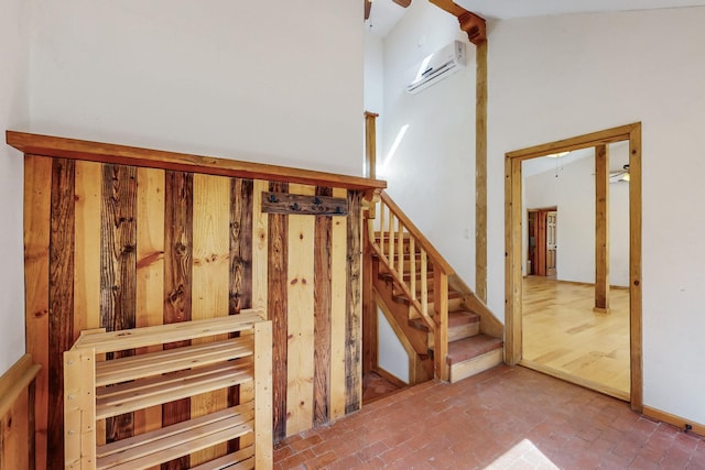 staircase featuring a wall unit AC, brick floor, and a high ceiling