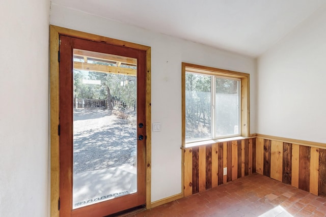 entryway with wood walls, brick floor, and a wainscoted wall