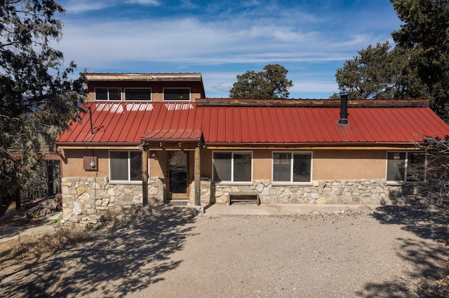 view of front of home featuring metal roof, stone siding, a patio area, and stucco siding