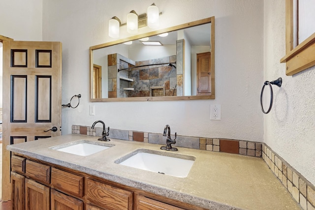 full bathroom featuring a textured wall, a sink, a shower stall, and double vanity