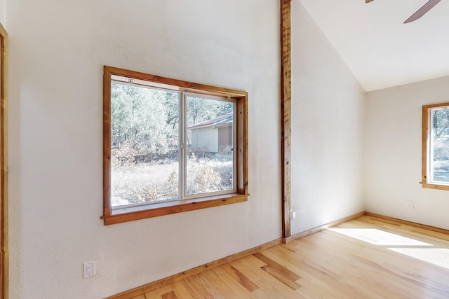 empty room featuring lofted ceiling, light wood-style floors, ceiling fan, and baseboards