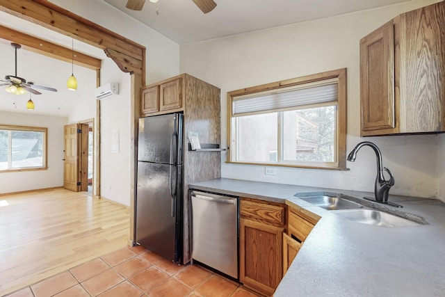 kitchen featuring freestanding refrigerator, brown cabinets, dishwasher, and a sink