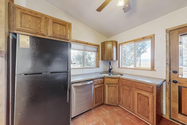 kitchen featuring brown cabinets, freestanding refrigerator, light countertops, stainless steel dishwasher, and a sink