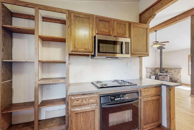 kitchen featuring light countertops, black oven, stainless steel microwave, and electric stovetop