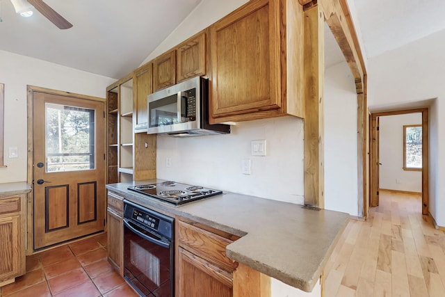 kitchen featuring a healthy amount of sunlight, black appliances, vaulted ceiling, and light countertops