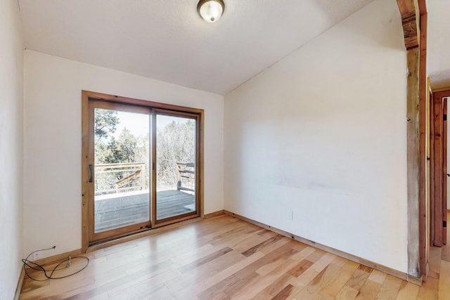 unfurnished room featuring vaulted ceiling, light wood-style flooring, and baseboards