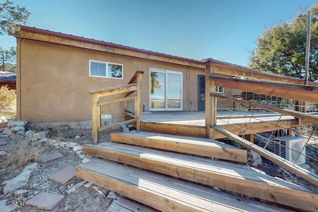 entrance to property featuring a deck and stucco siding