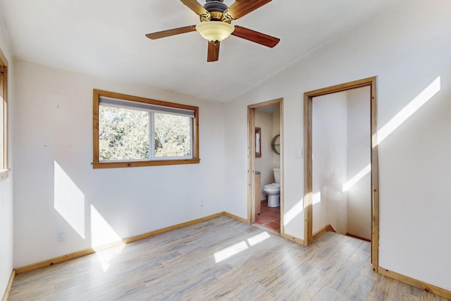 unfurnished bedroom with light wood-style floors, baseboards, vaulted ceiling, and ensuite bathroom