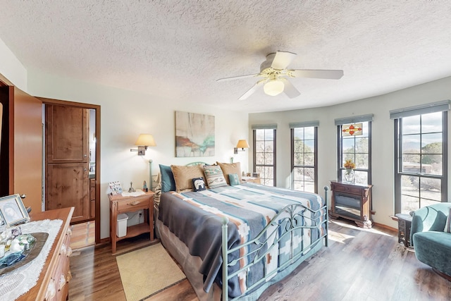 bedroom with dark wood-type flooring, ceiling fan, a textured ceiling, and baseboards