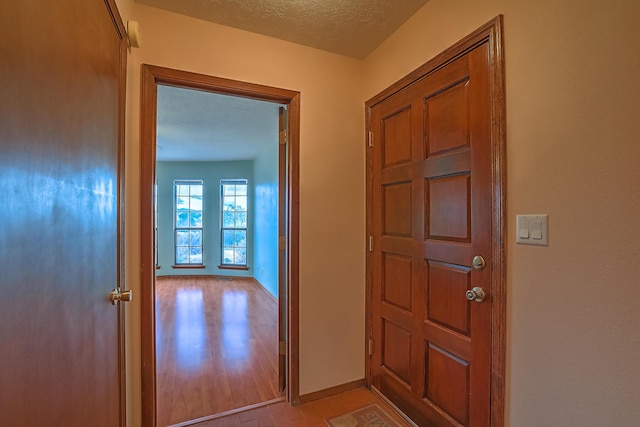 foyer with a textured ceiling, light wood-style flooring, and baseboards