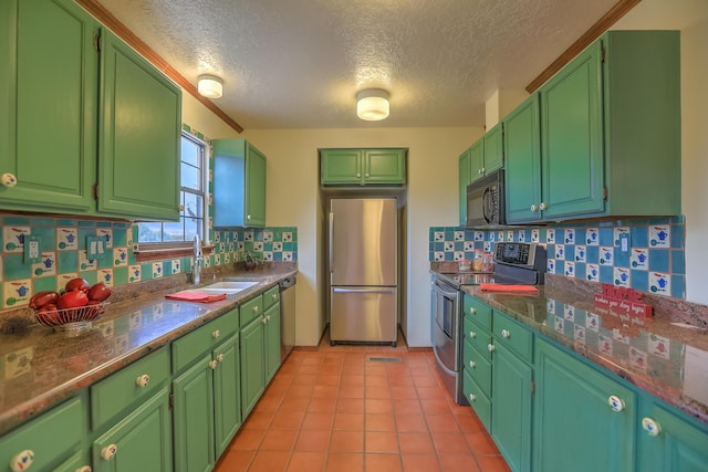 kitchen featuring dark countertops, appliances with stainless steel finishes, a sink, and light tile patterned flooring