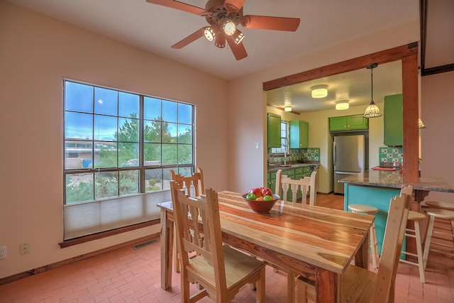 dining space featuring brick floor, visible vents, and a ceiling fan