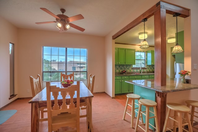 dining area with brick floor, ceiling fan, and baseboards