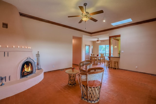 living area with brick floor, a skylight, crown molding, a lit fireplace, and baseboards