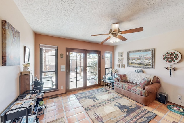 living area featuring a textured ceiling, french doors, light tile patterned floors, and a ceiling fan