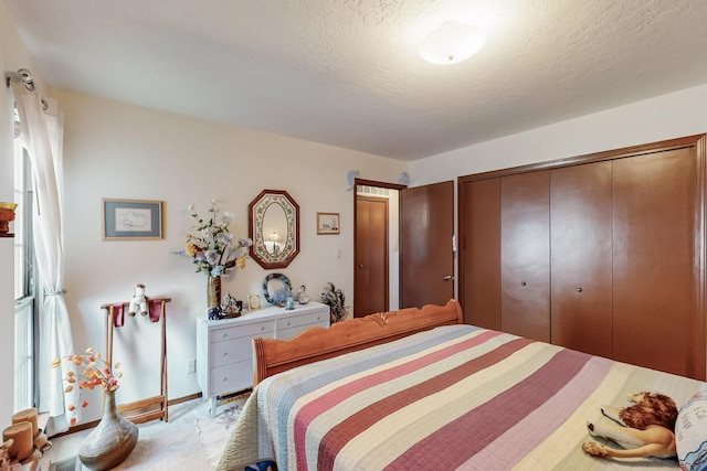 bedroom featuring light carpet, a closet, baseboards, and a textured ceiling