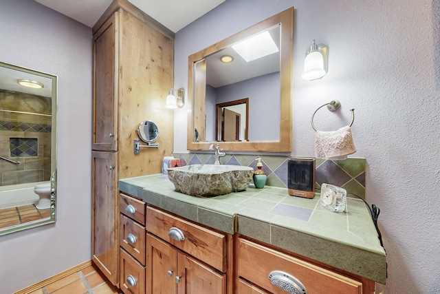 bathroom with a skylight, tile patterned flooring, and vanity